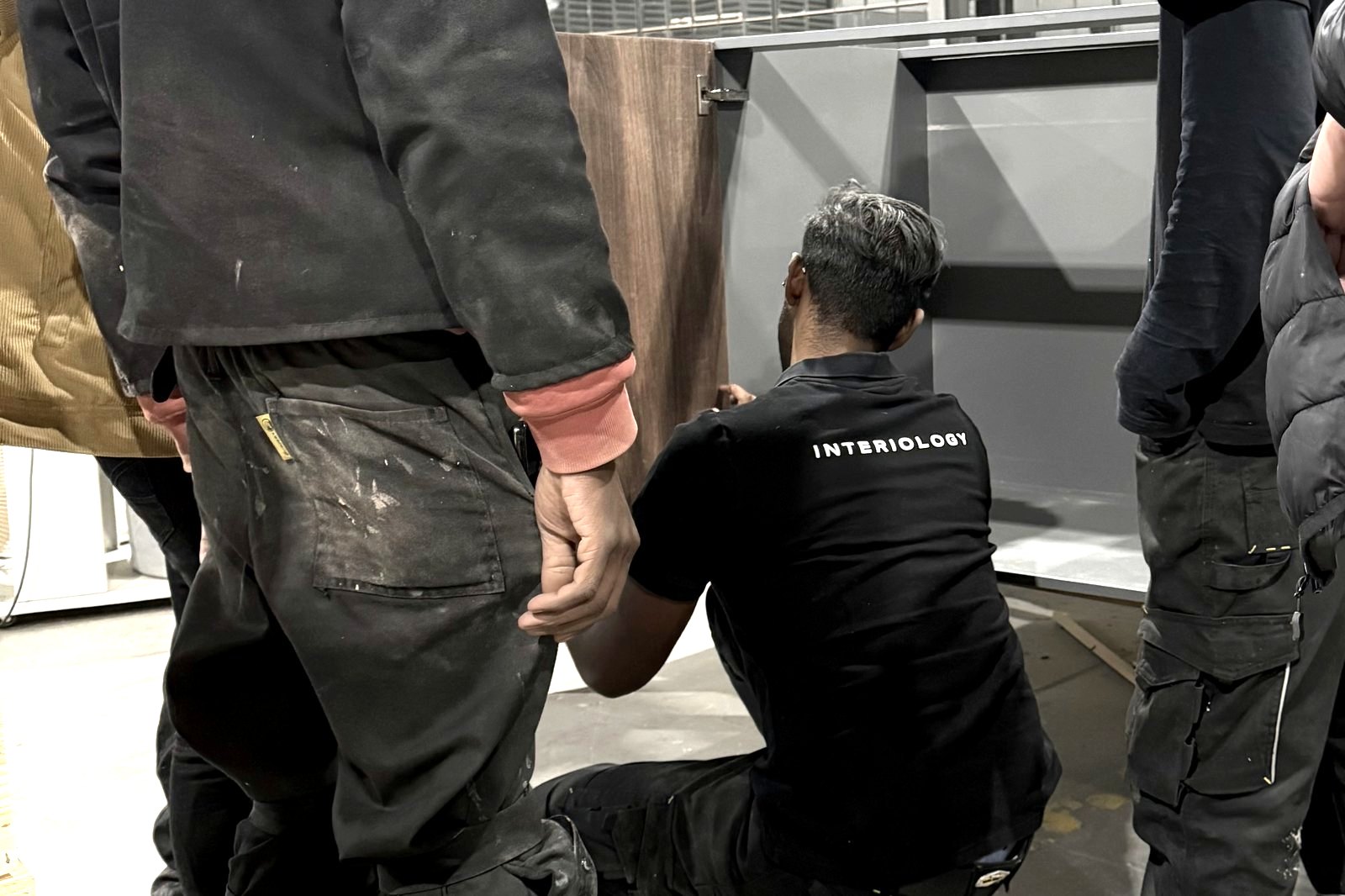 An Interiology™ team fitting a walnut cabinet on the workshop floor