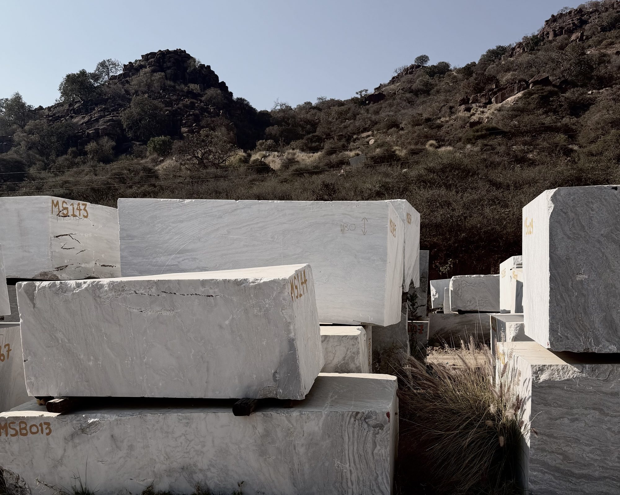 White marble blocks stacked at an African quarry, raw stone sourced by Interiology
